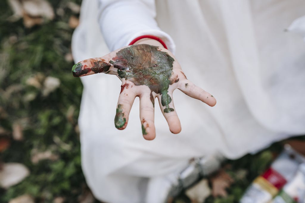 A child's hand covered in paint during outdoor playtime, capturing creativity and exploration.