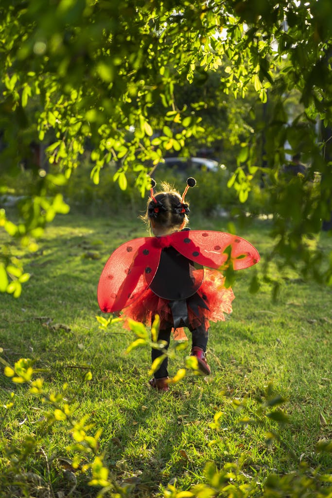 Charming scene of a child with ladybug wings running freely in a sunny park.