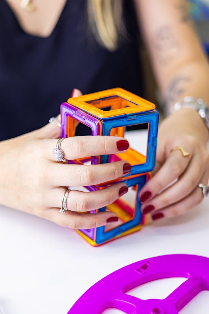 Hands constructing with vibrant magnetic tiles, showcasing creativity and play